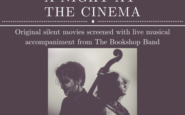 A dark grey square poster with text and an image of 2 people. In the top quarter of the poster, large capitalised text at the top reads 'A NIGHT AT THE CINEMA' with decorative beaded lines above and below, reminiscent of vintage poster. Below, smaller text reads 'Original silent movies screened with live musical accompaniment from The Bookshop Band'. The bottom half of the poster shows a centred square black and white photo of white couple in their thirties, seen from chest up. They stand back to back. The man on the left looks down, the woman on the right looks up and holds a cello by the neck over her left shoulder. Beneath the image, text reads 'September 2021'.