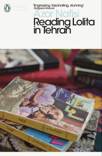 The book cover for ‘Reading Lolita in Tehran’ by Azar Nafisi. The background is a photograph of the book ‘Lolita’ on top of a stack of books. The top of the cover is white and the title and author’s name are displayed there in black and pale blue text.