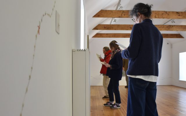 Participants in a writing workshop at CAMPLE LINE take notes whilst observing artworks in an exhibition by Amalia Pica in Autumn 2025