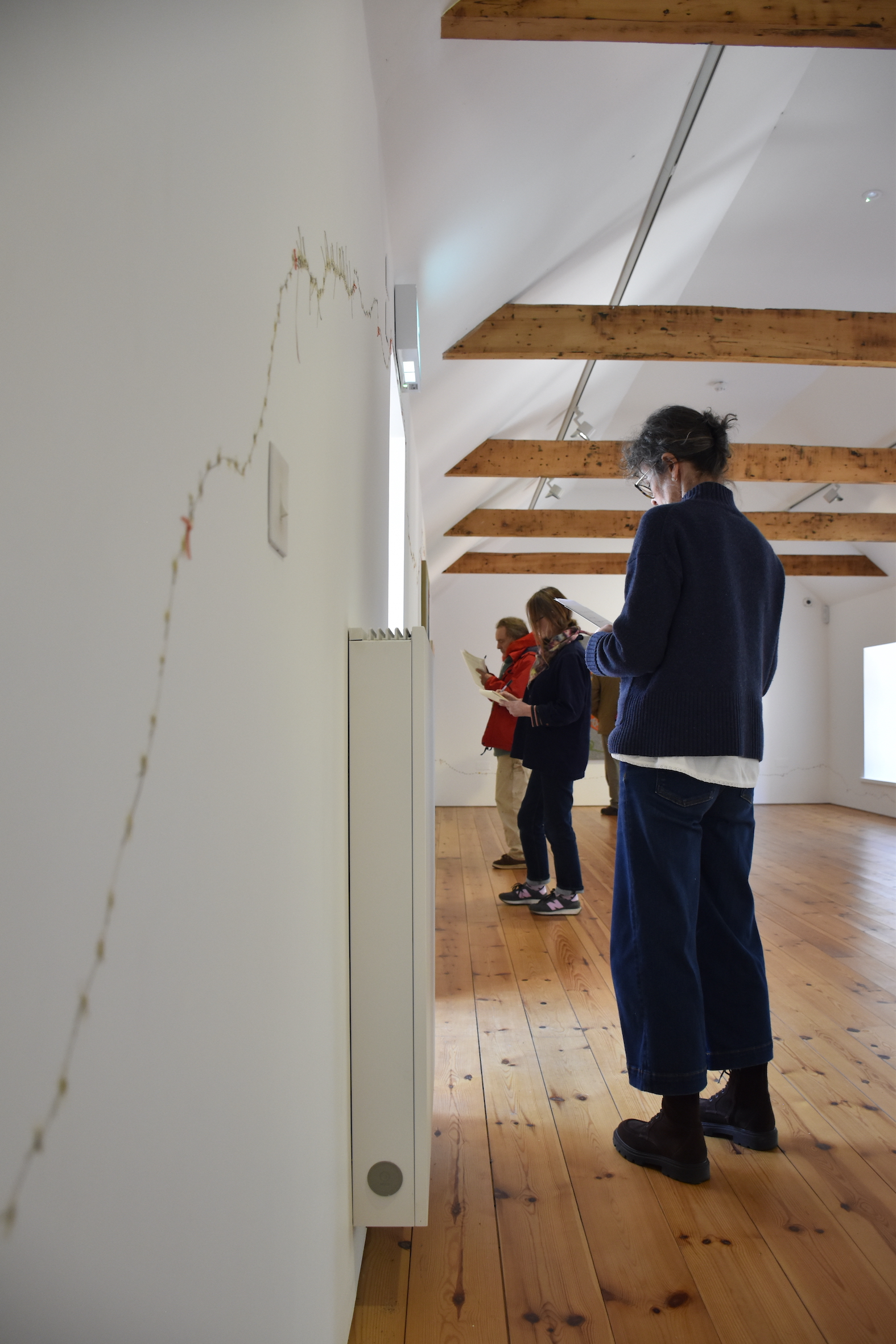 Participants in a writing workshop at CAMPLE LINE take notes whilst observing artworks in an exhibition by Amalia Pica in Autumn 2025