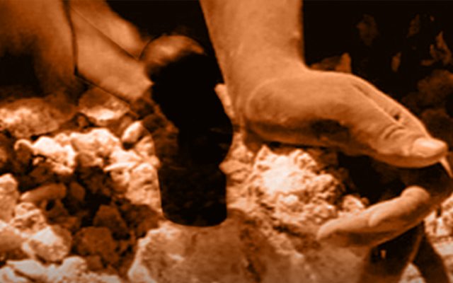 A close up of a person's hands. In their left hand they hold a small, rough, pale coloured stone. In their right they hold a small iron hammer which they are hitting against another rock below.